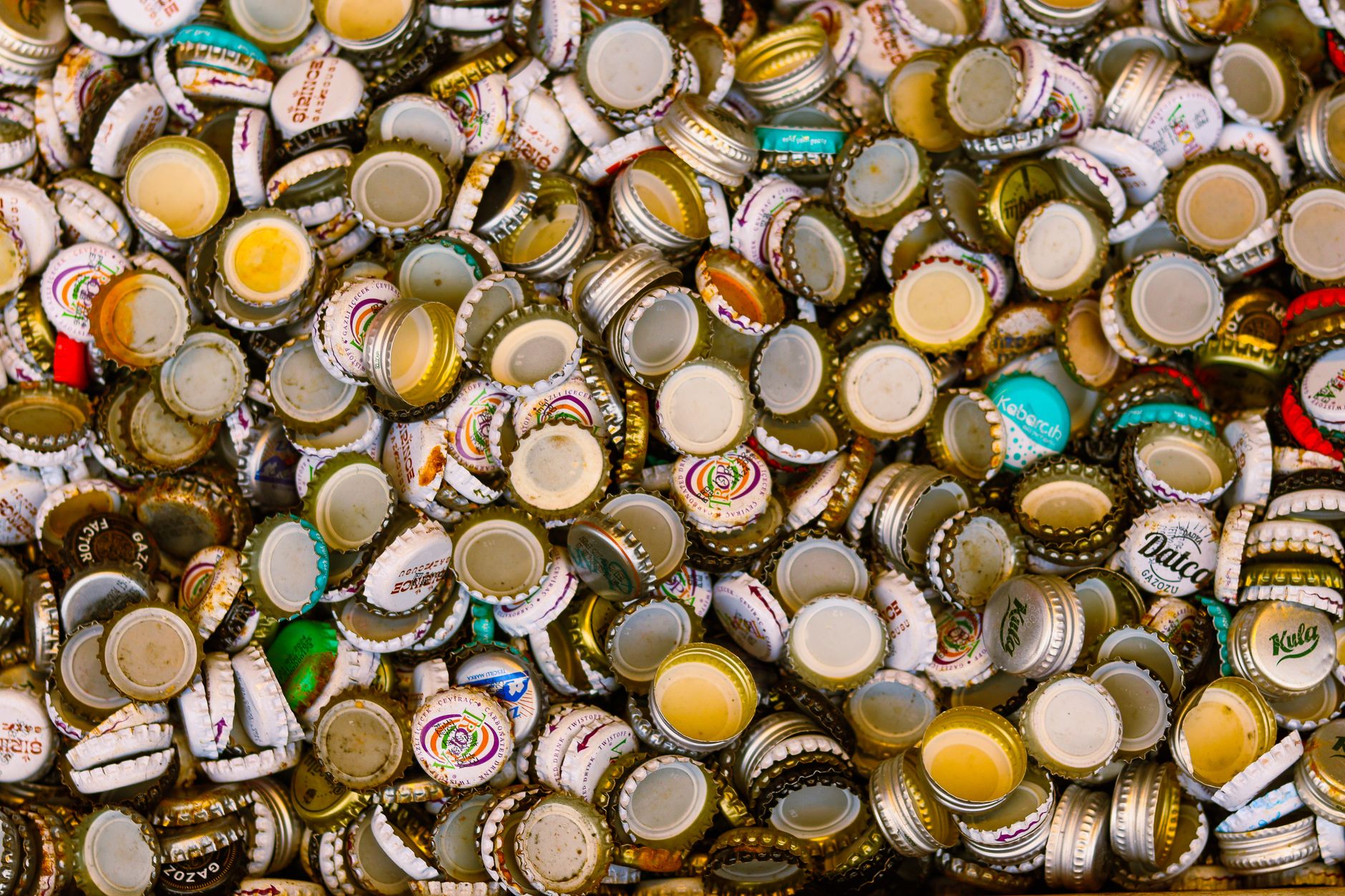 Close-up of multiple colorful bottle caps laid out for recycling and art projects.