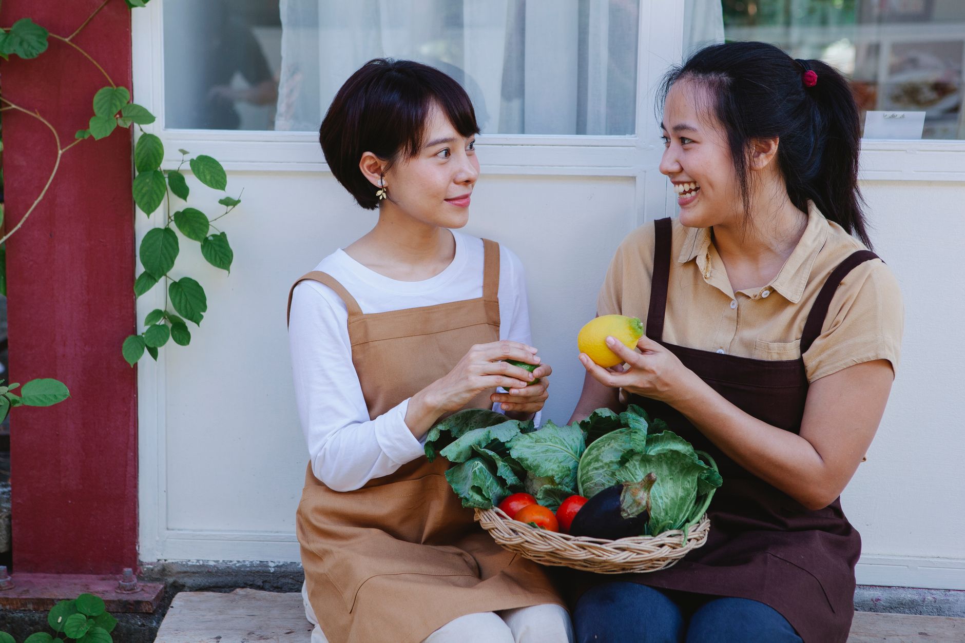 Two women enjoying fresh vegetables in a rustic outdoor setting, holding lemons.