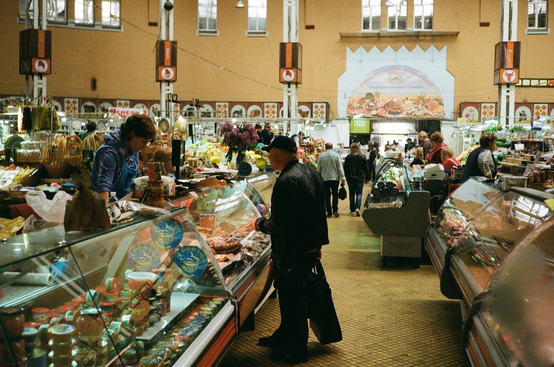 Indoor market in Kyiv bustling with shoppers exploring fresh groceries and market stalls.