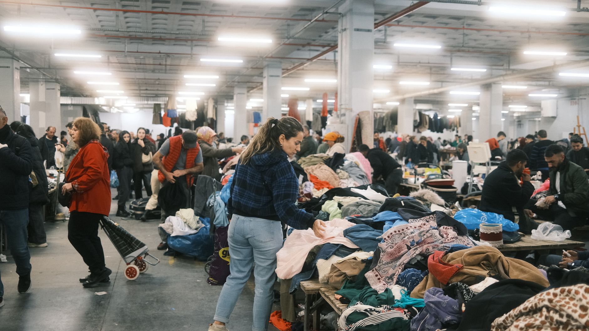 Crowded indoor flea market in Istanbul with people browsing textiles and clothes.