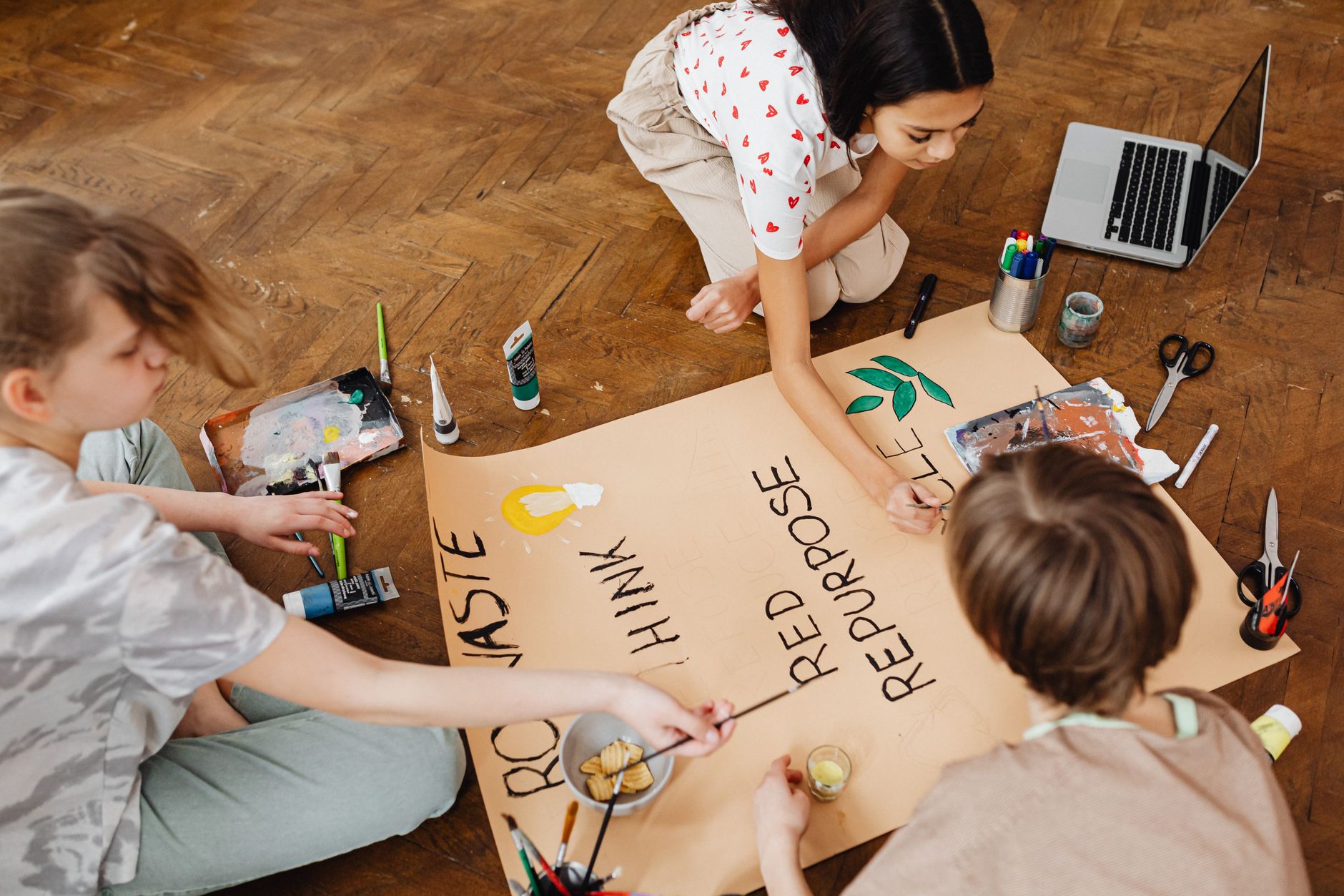 Teens engaged in art project focused on recycling with paints.