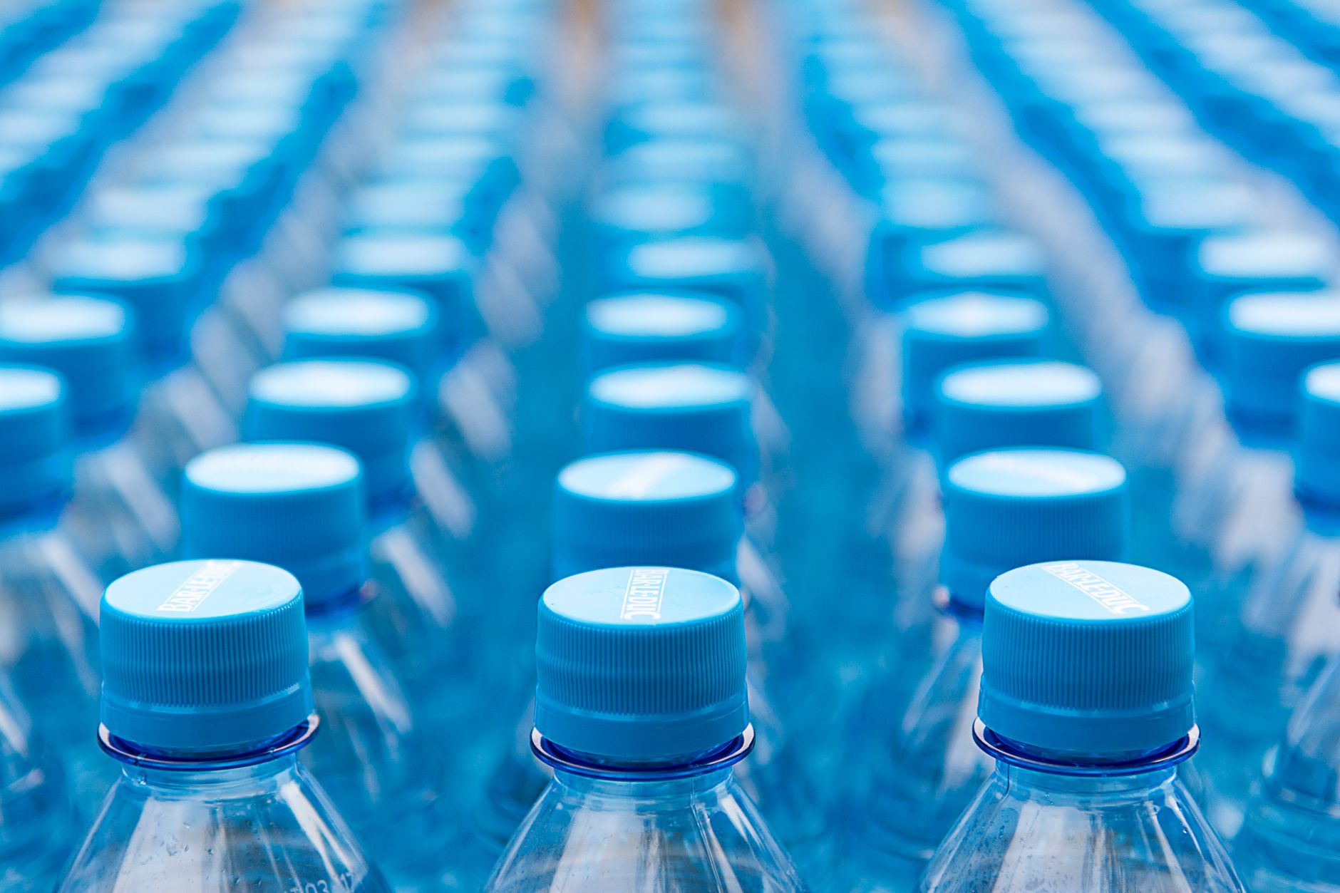 Array of blue plastic water bottles with caps arranged in a pattern. Ideal for recycling and packaging themes.