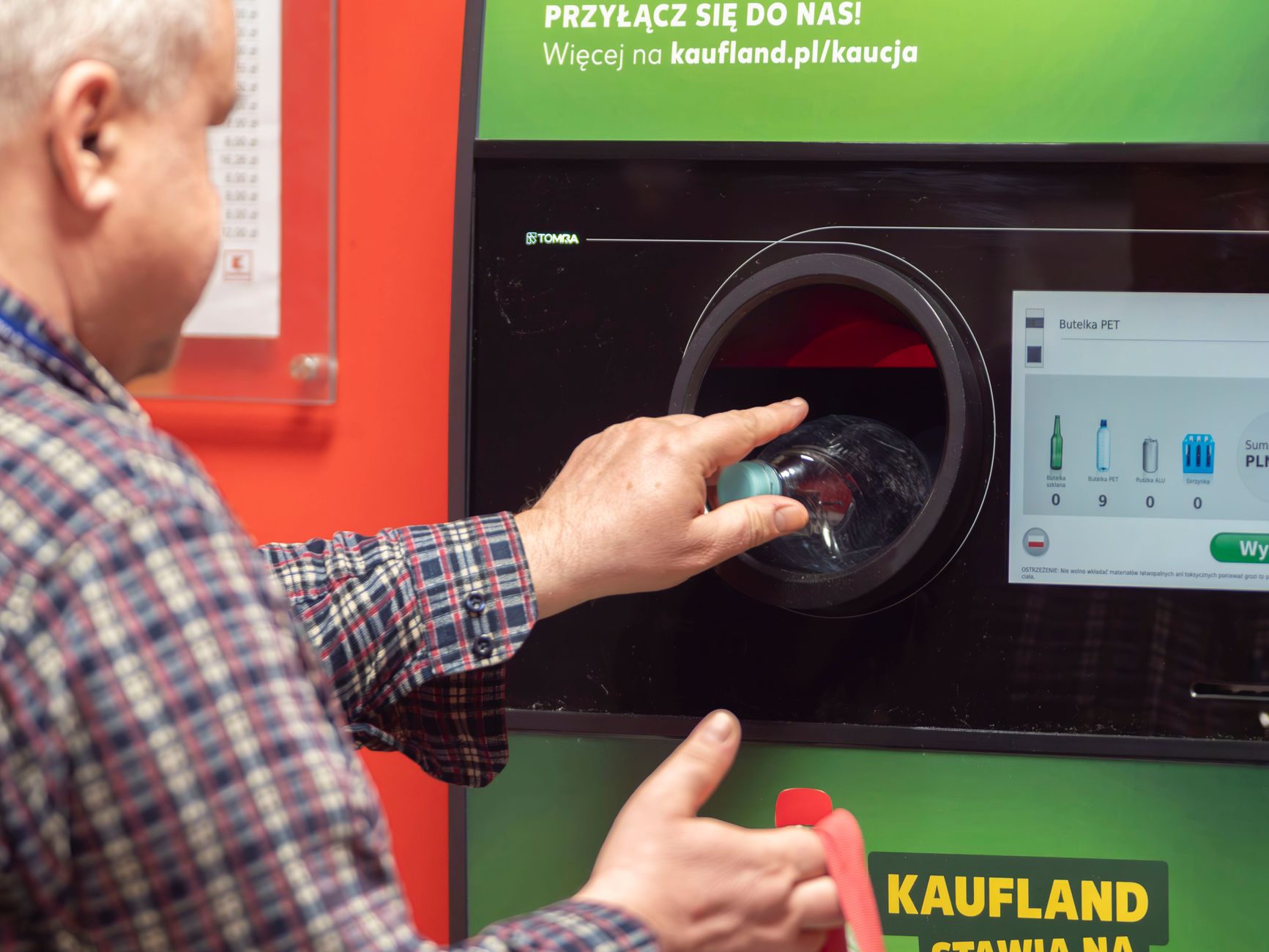 A man recycling plastic bottles at a reverse vending machine in Kaufland, Wrocław, Poland.
