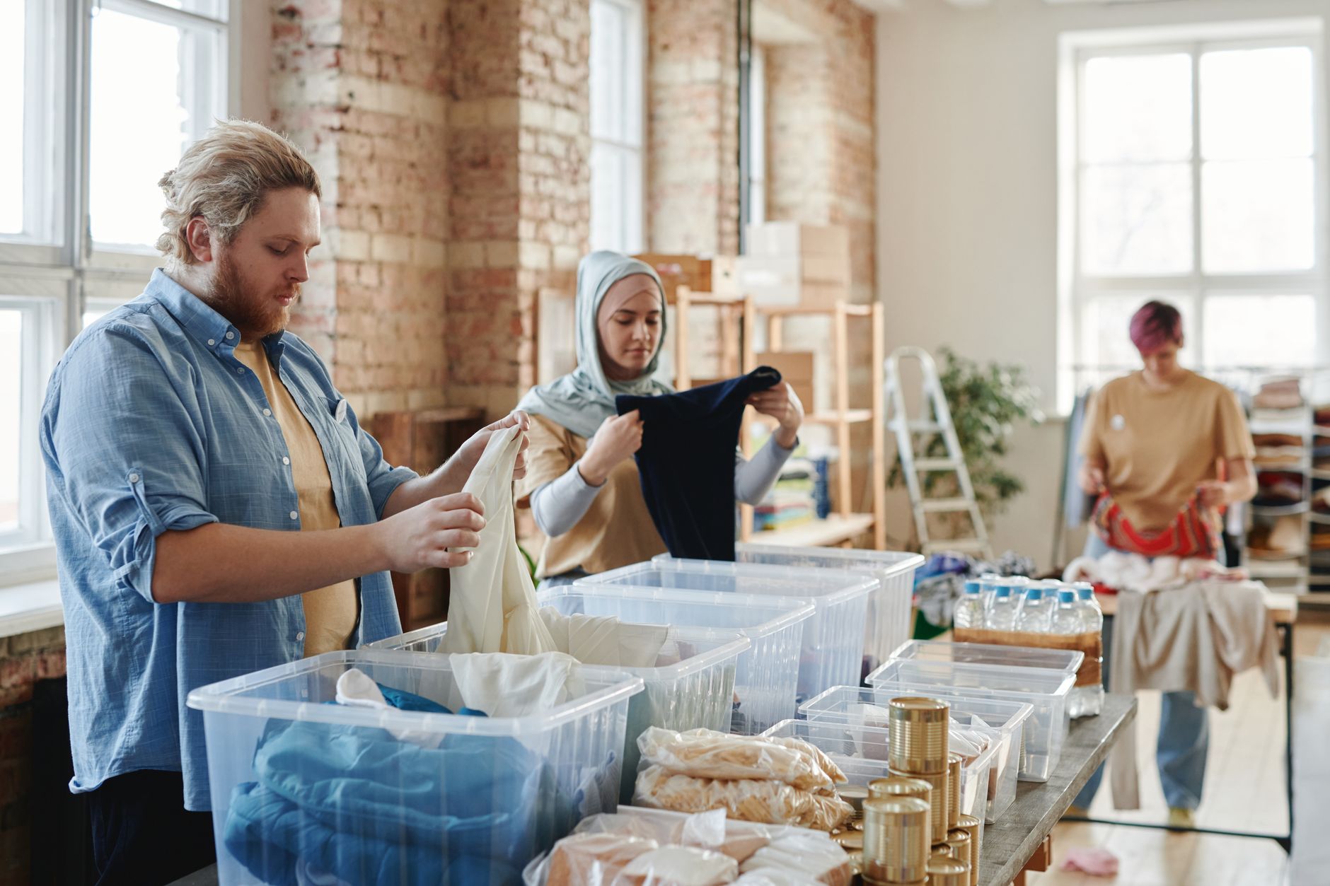 A diverse group of volunteers sorting clothes and goods in a well-lit loft.