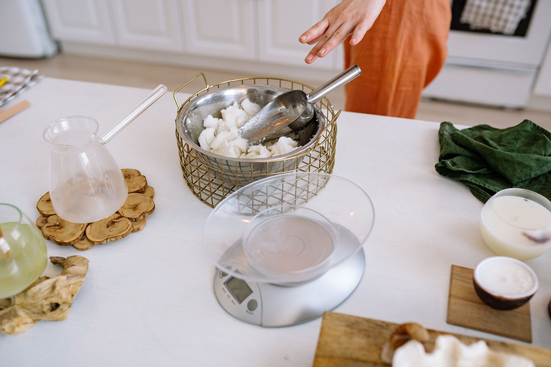 A person crafting handmade candles in a cozy kitchen with natural materials.