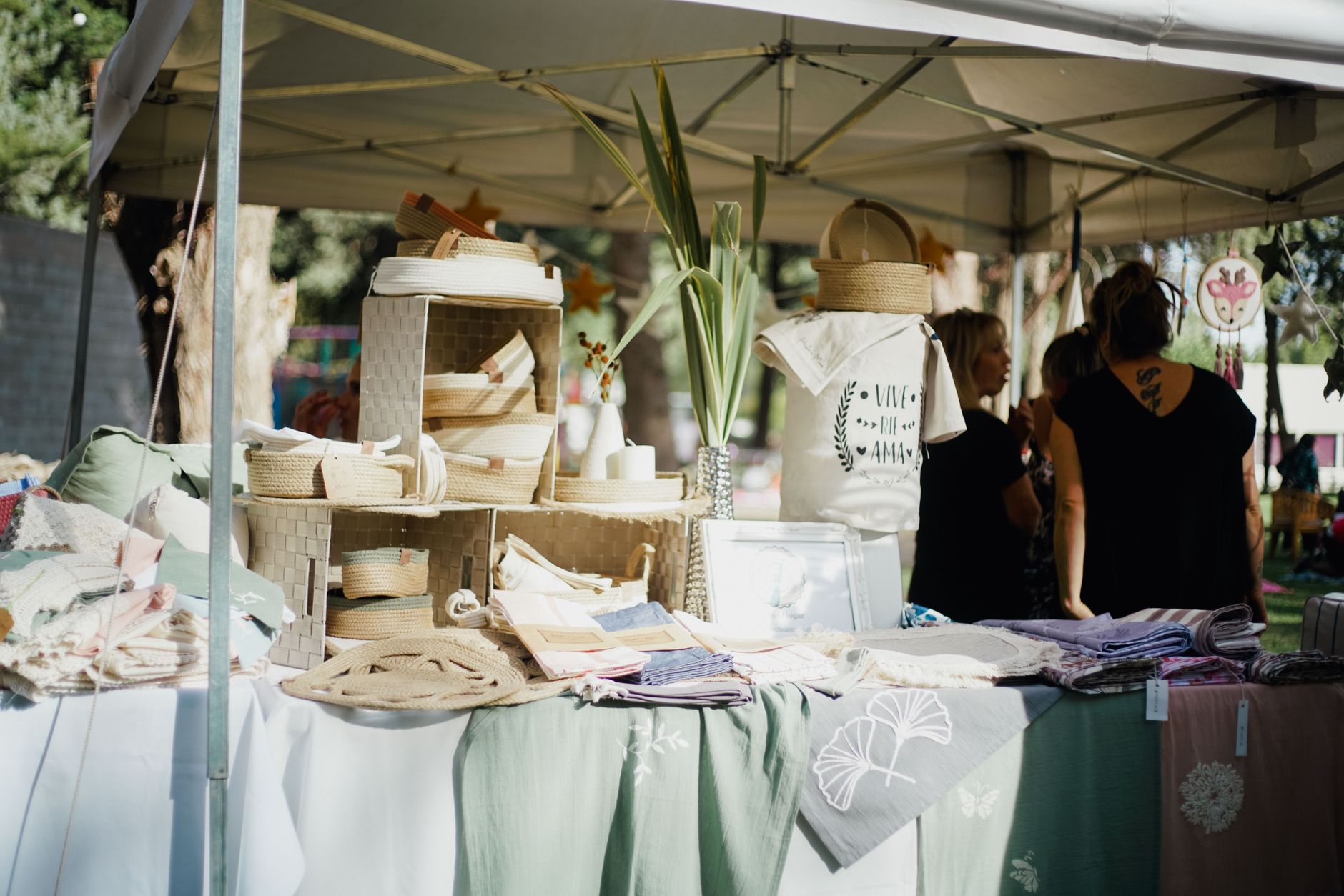 A vibrant outdoor market stall showcasing handcrafted textiles, baskets, and decor items under a canopy.