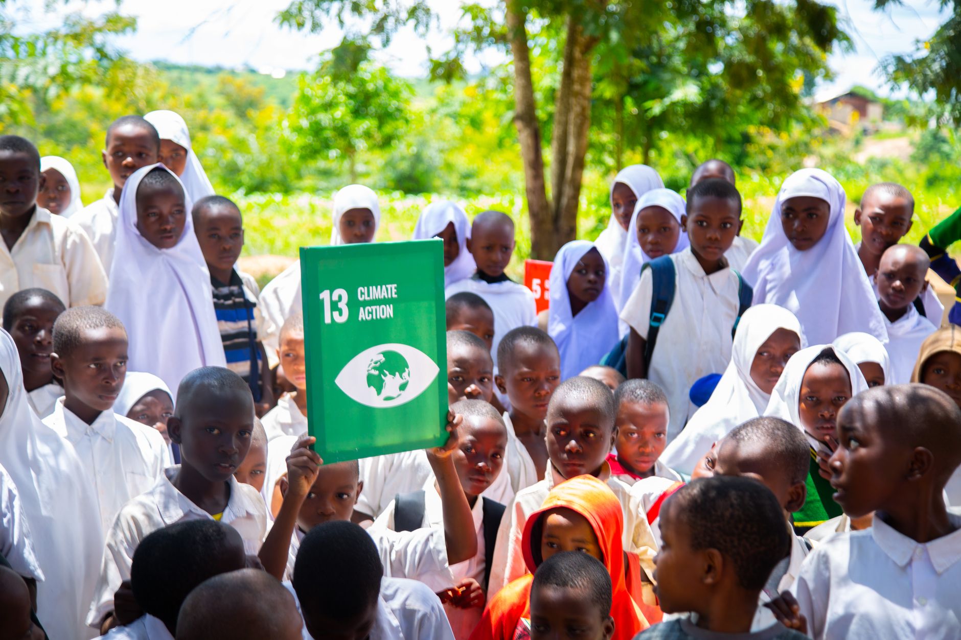 Group of children holding a Climate Action sign, promoting awareness for sustainable development.