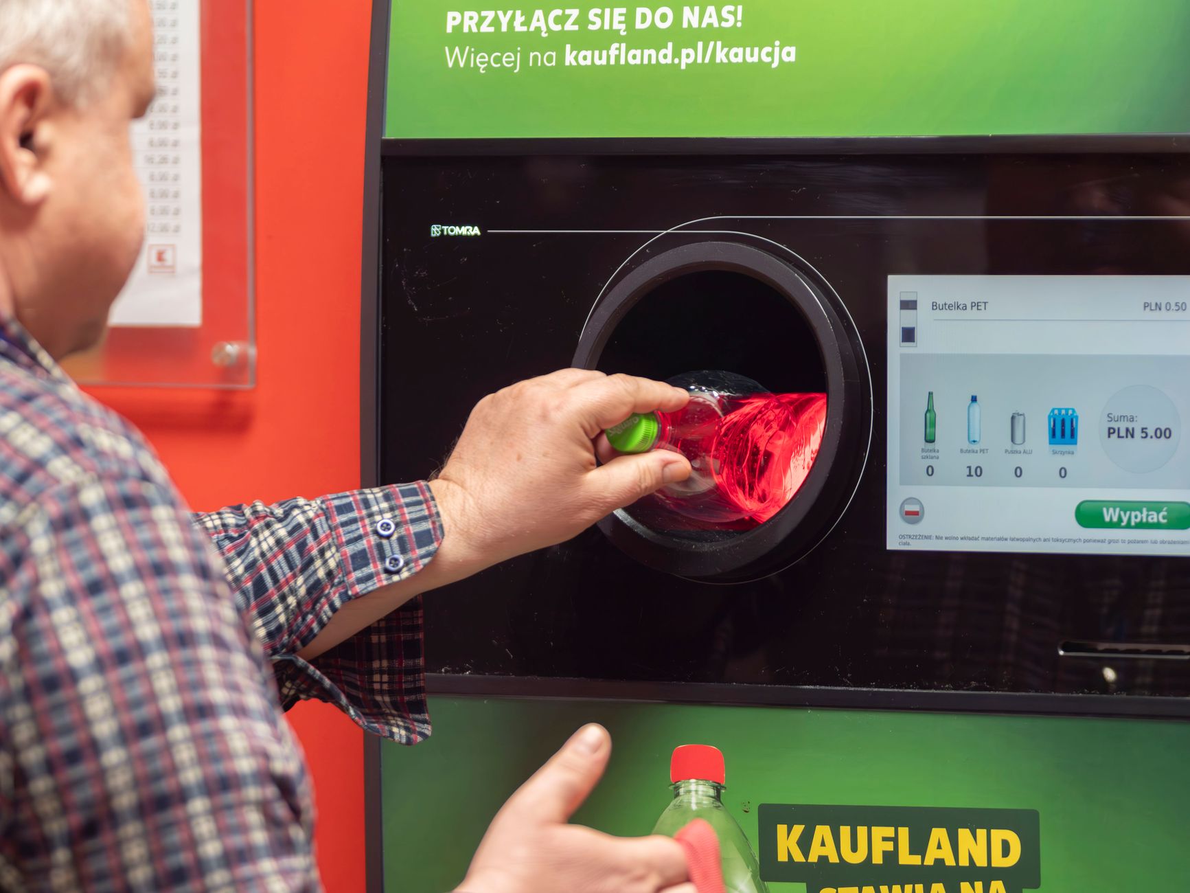 Man recycling bottle at a reverse vending machine in Wrocław, Poland.