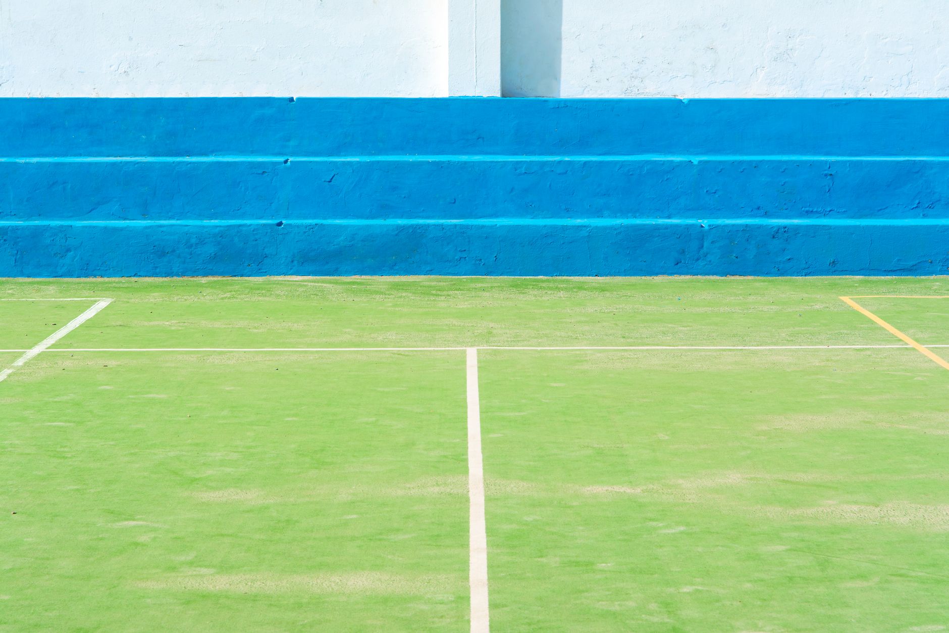 A vibrant sports field with green turf and blue stepped seating, perfect for recreational activities.