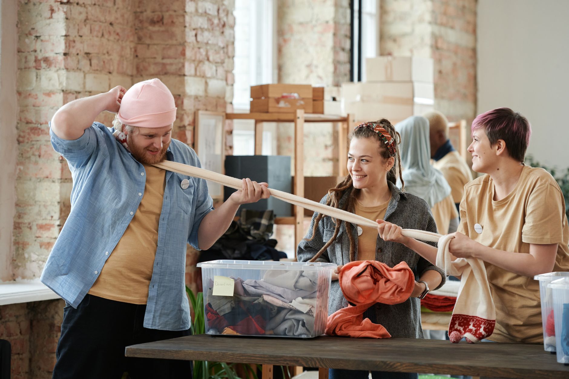 Volunteers having fun while sorting clothes at a charity event indoors.