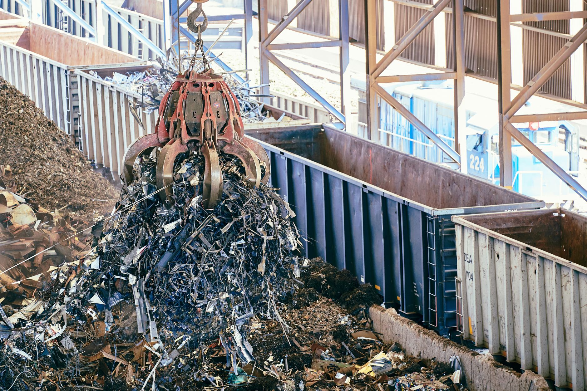 An industrial claw crane lifts metal scrap in a recycling facility, showcasing efficient waste management.