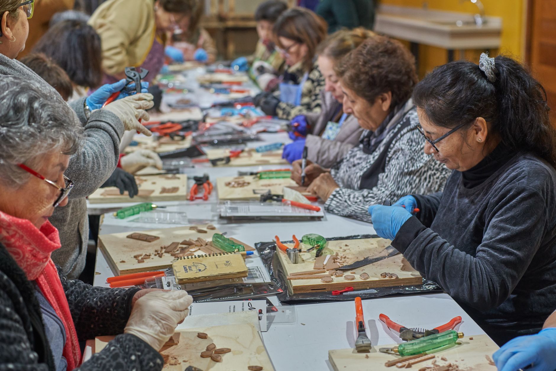 Senior women participate in a creative mosaic workshop in Lautaro, Chile, fostering community and creativity.