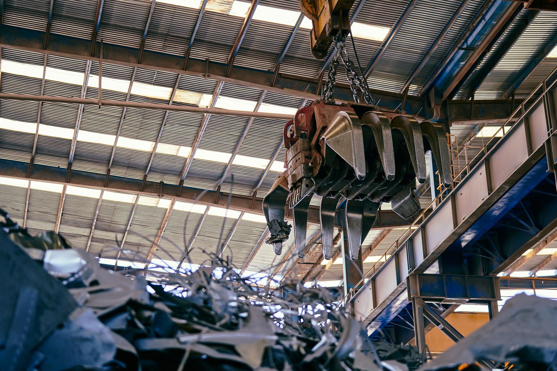 Interior view of a facility with a crane handling metal scrap.
