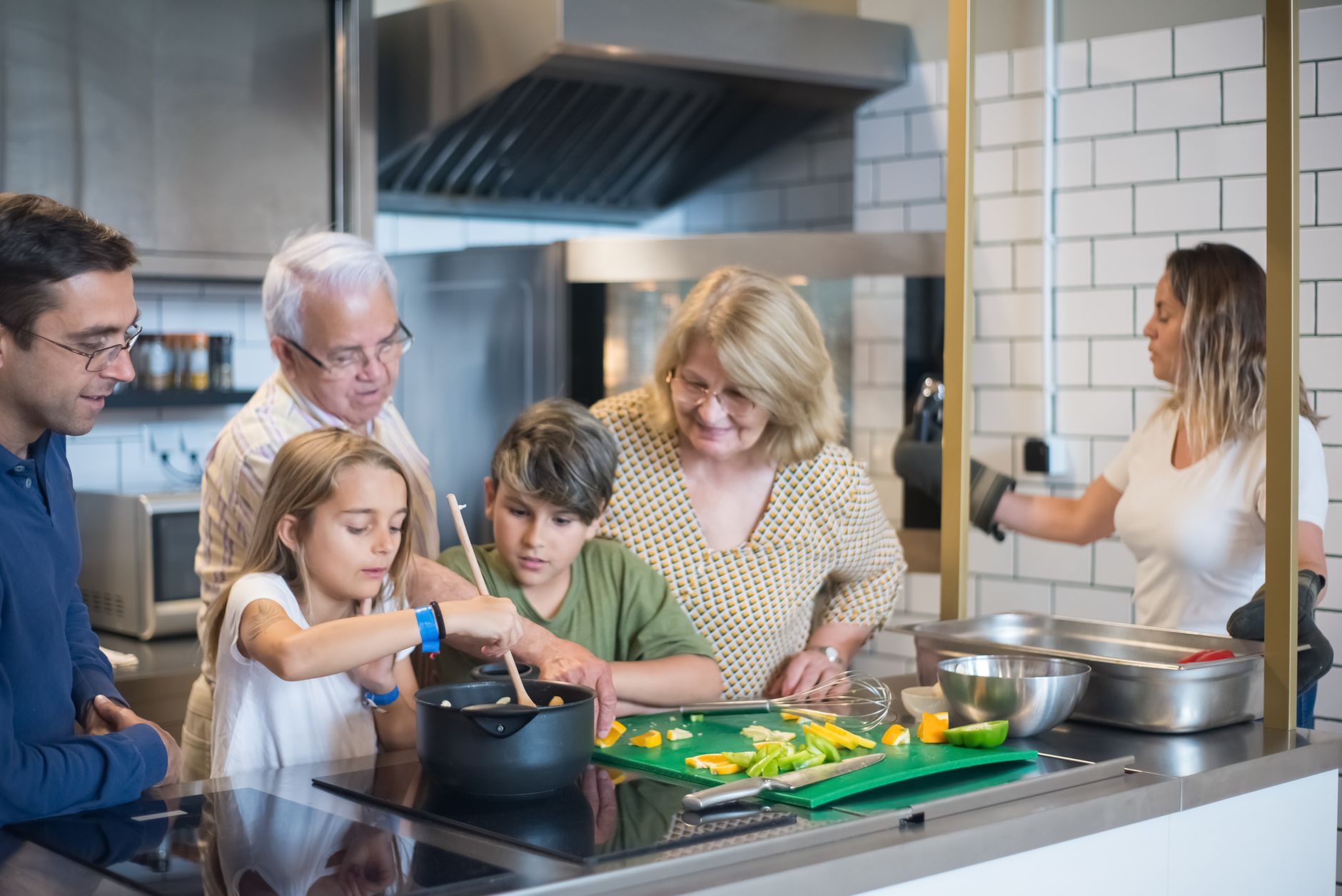 Multi-generational family enjoying cooking together in a modern kitchen setting.