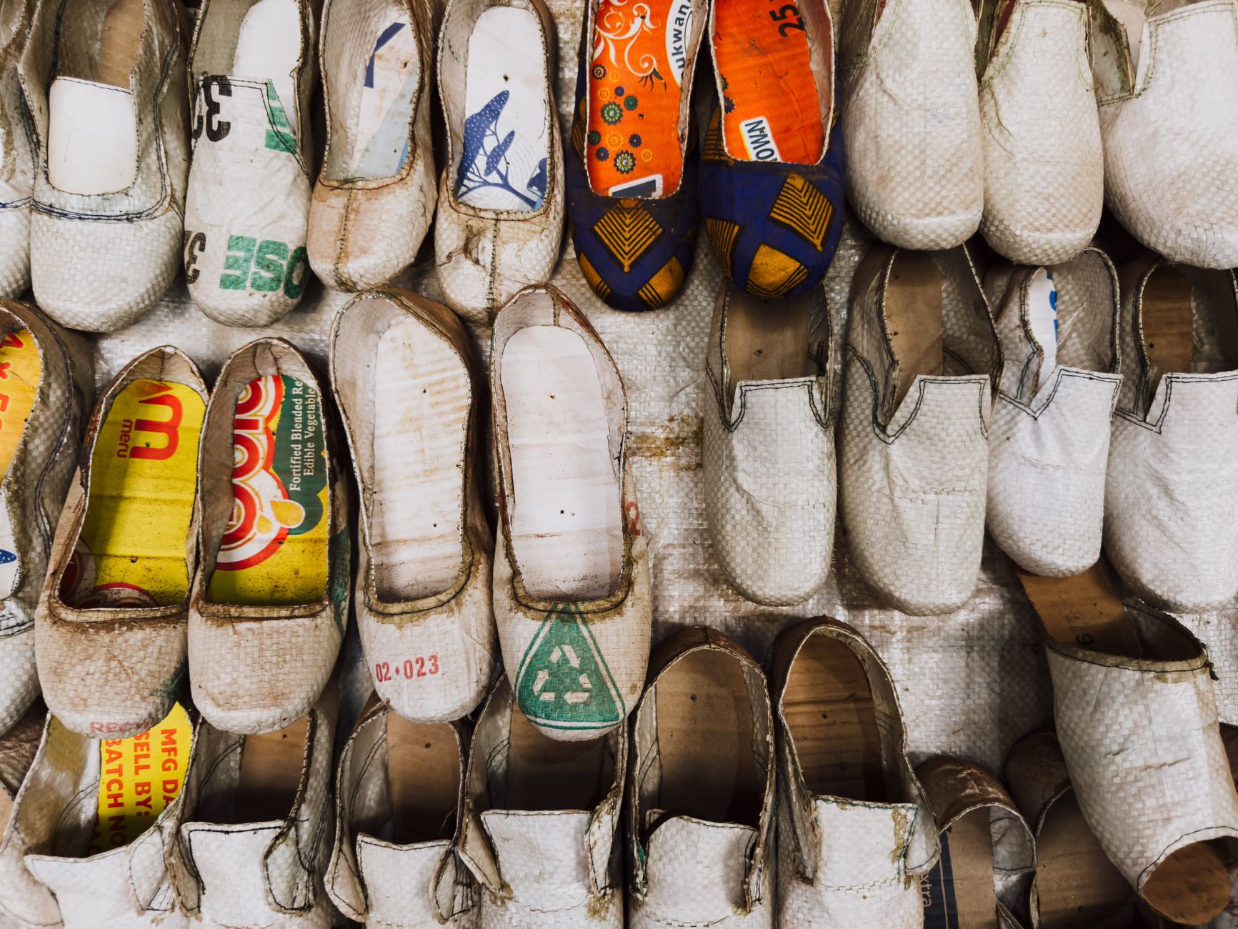 Unique shoes crafted from recycled materials in a Ugandan market display.