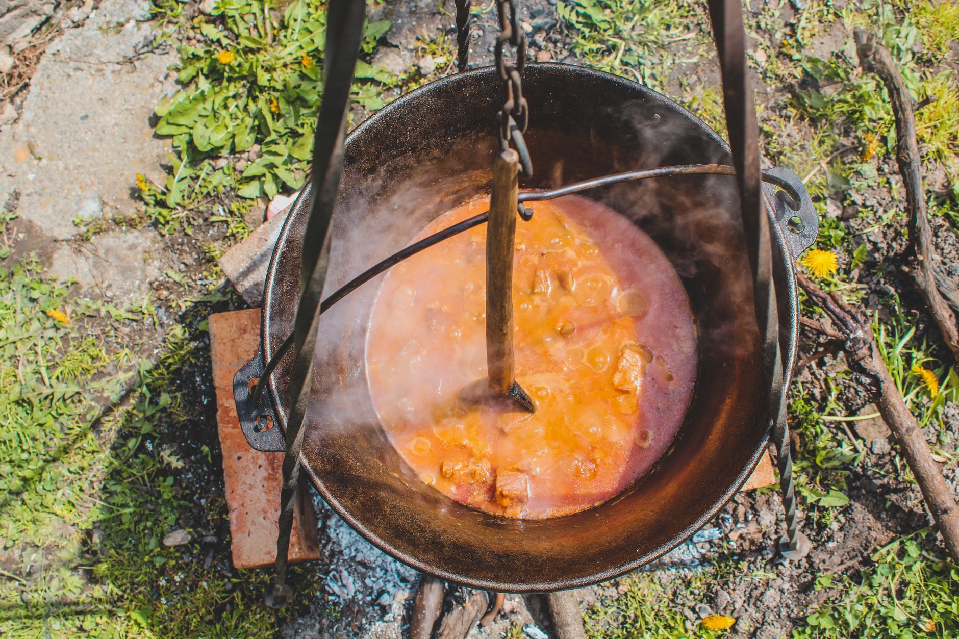Aerial view of a traditional stew being cooked in an iron cauldron outdoors in Romania.