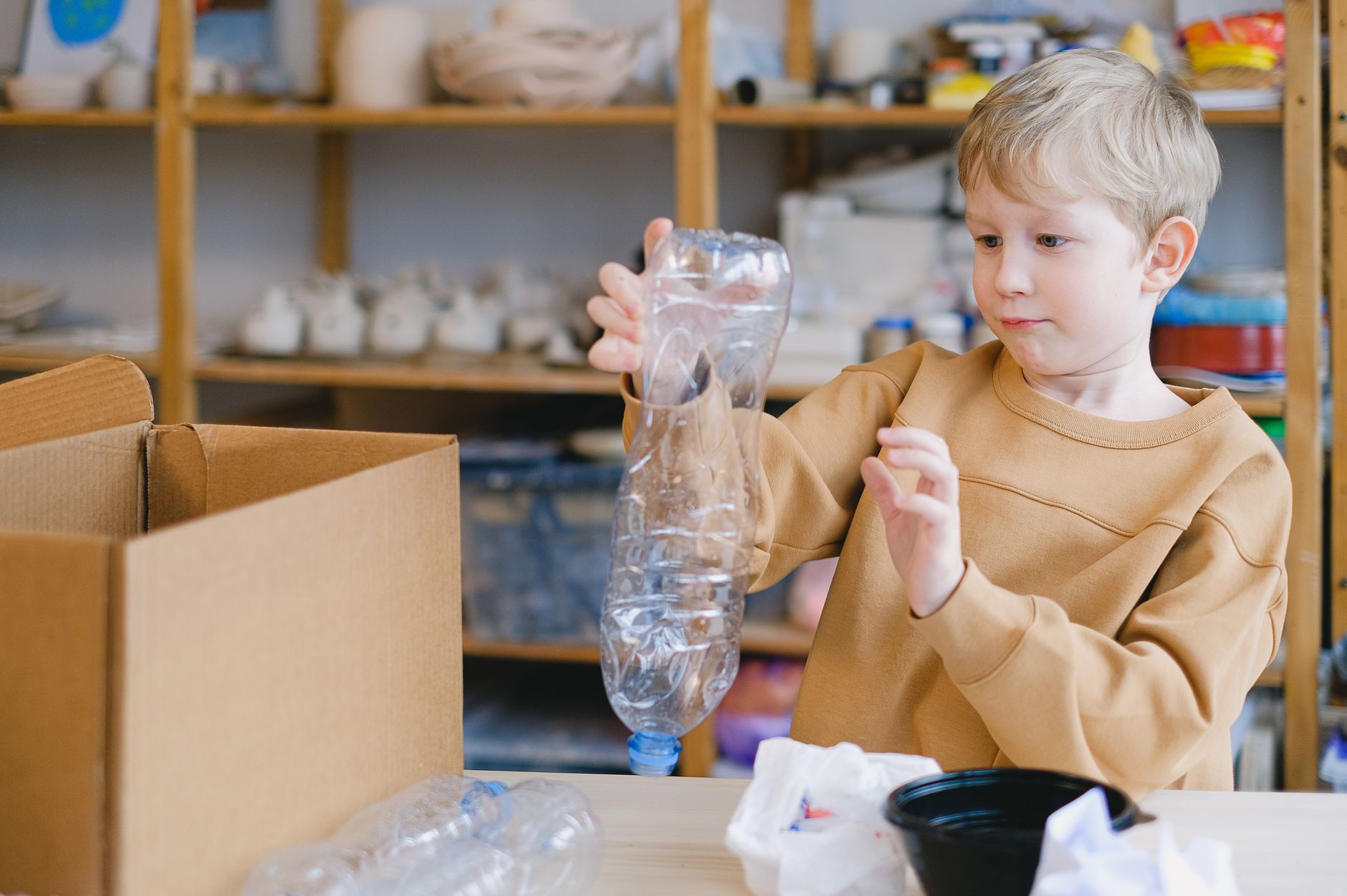Young child sorting plastic bottles for recycling, promoting eco-friendly habits.
