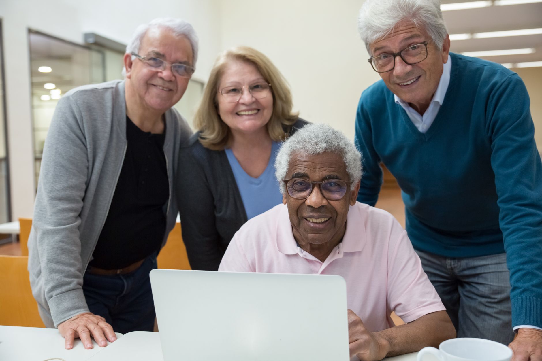 Four senior adults enjoying a computer learning session in a classroom setting.