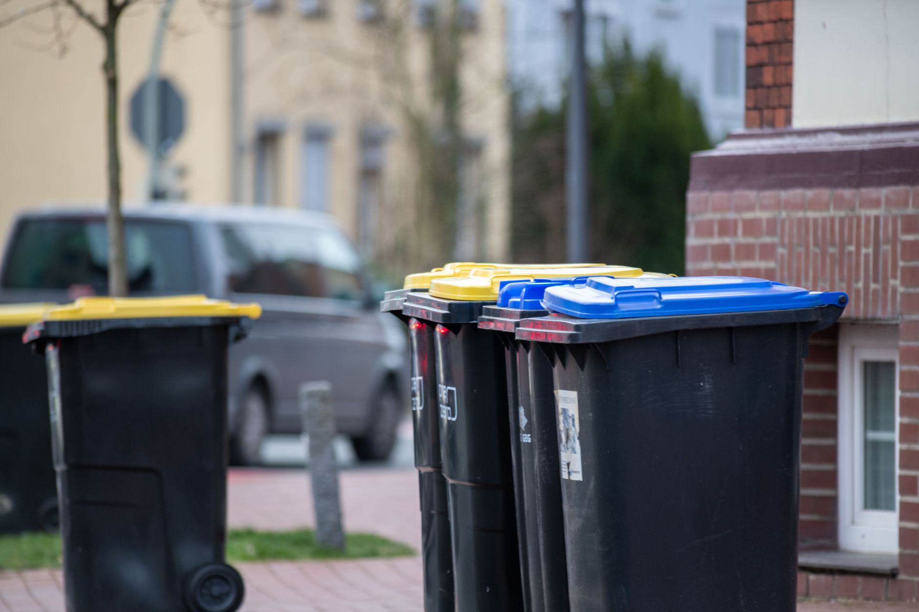 Color-coded trash bins on a city street in Gütersloh, Germany, showcasing urban waste management.