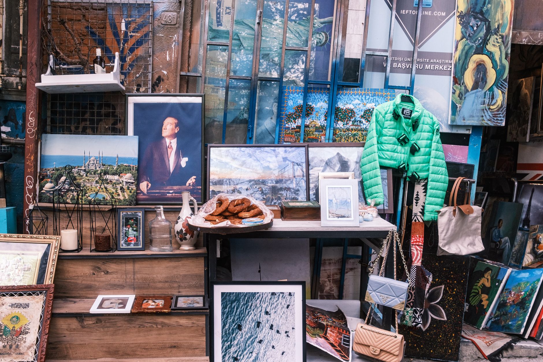 Colorful vintage market stall featuring art, clothes, and bags.