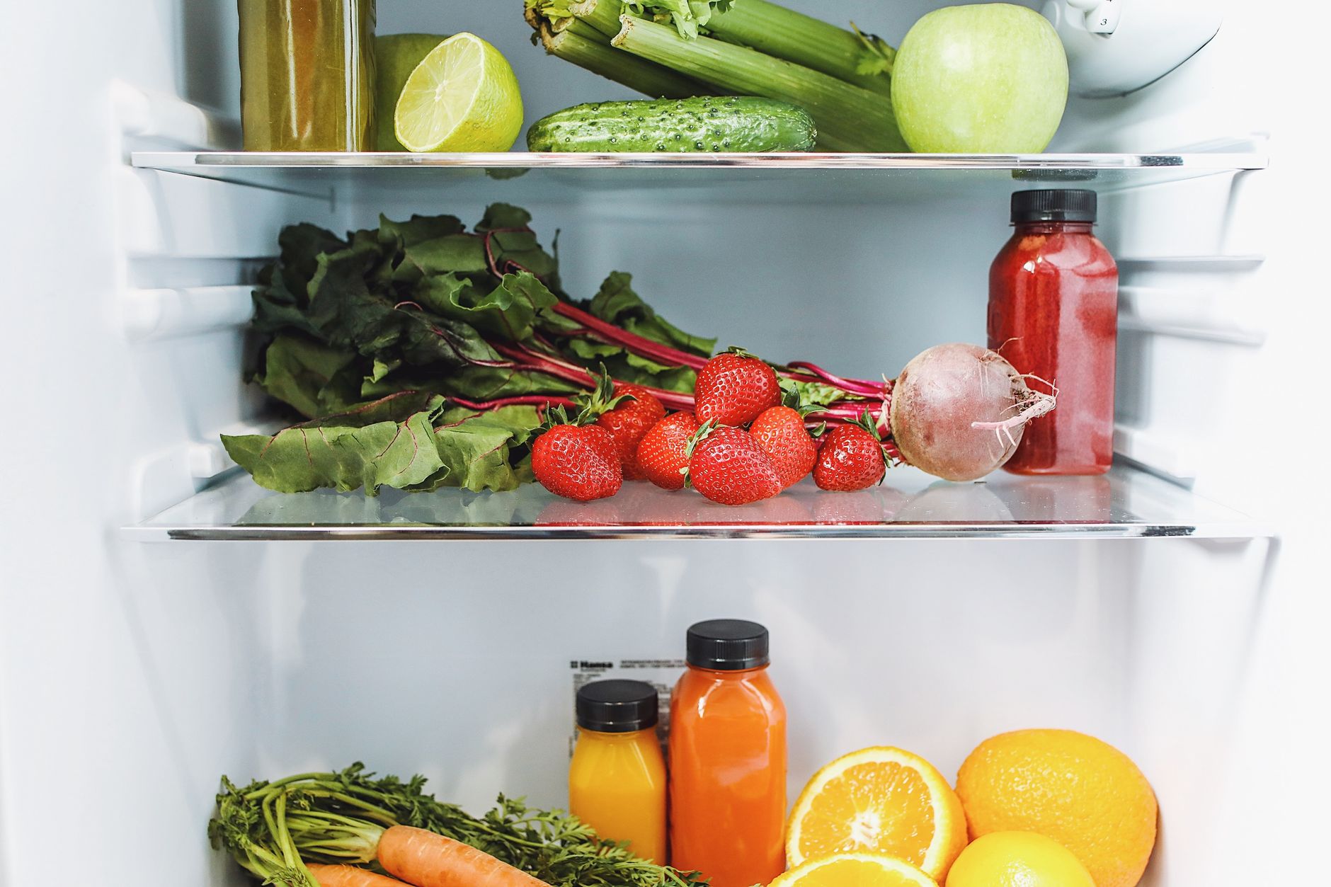 Colorful array of fresh fruits and vegetables neatly arranged in a refrigerator.