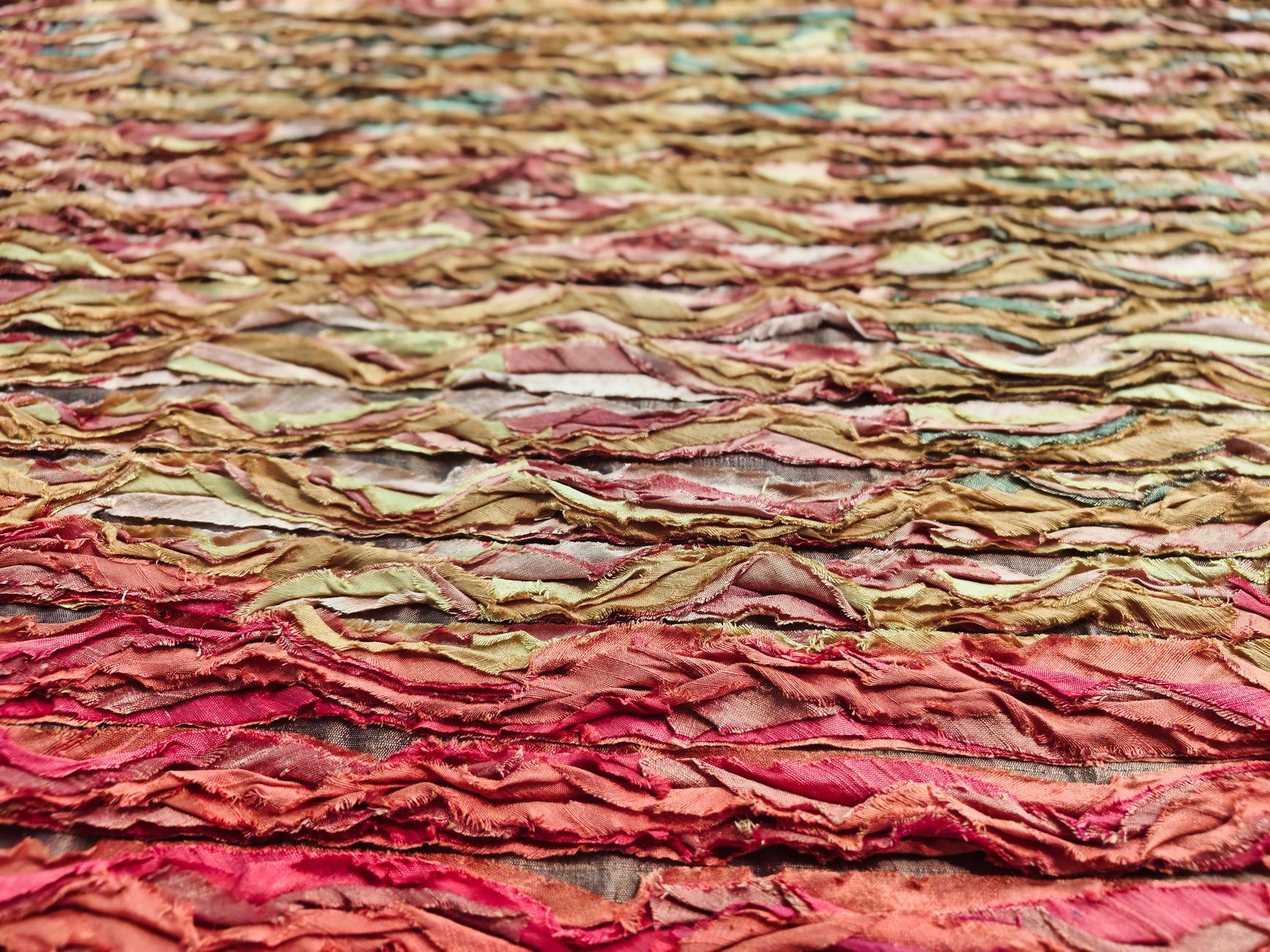 Colorful abstract textile art featuring layered and textured fabric swatches in warm tones.