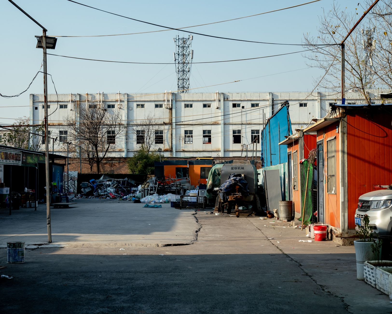 An urban industrial yard featuring colorful containers and a white building backdrop.
